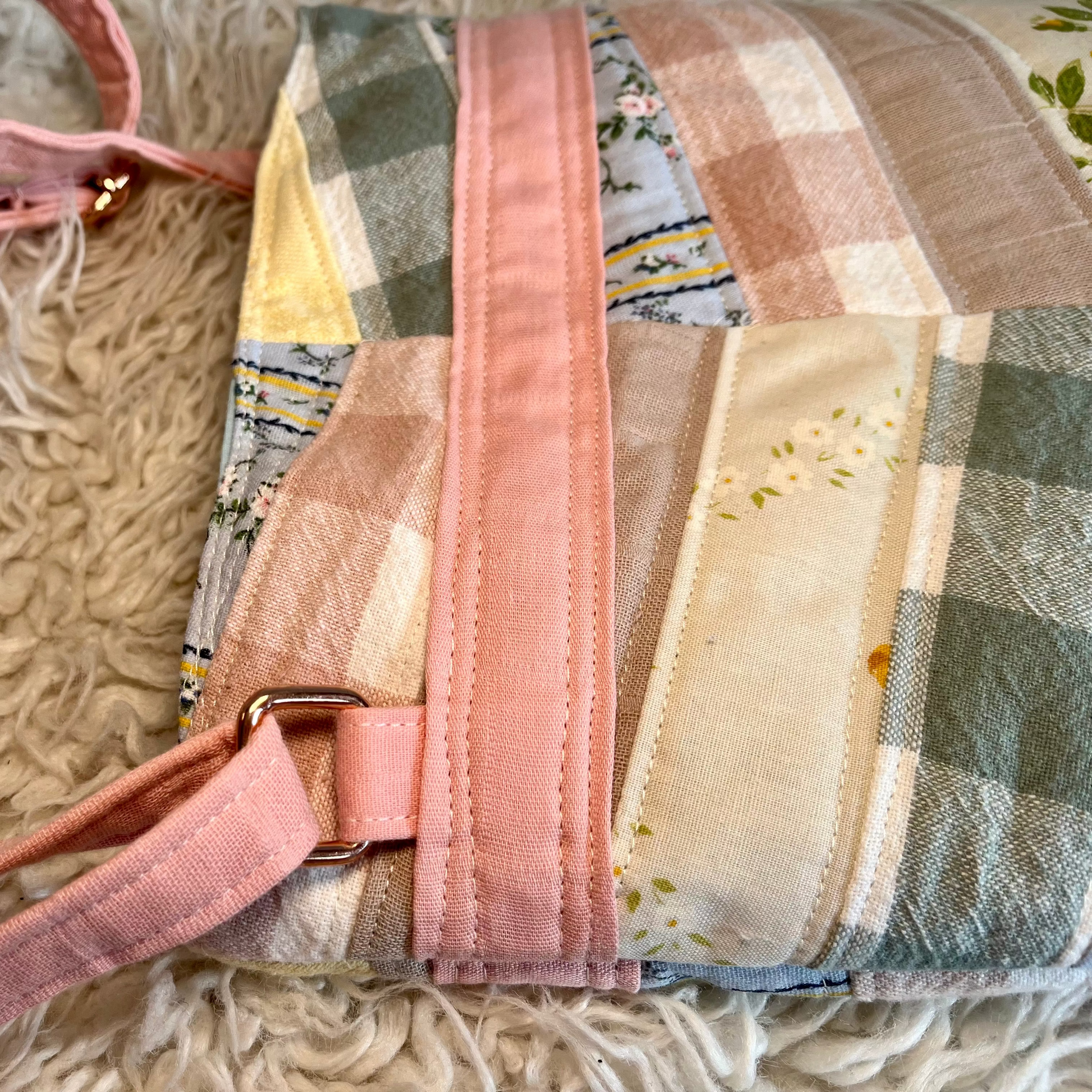 Patchwork bag with pink strap on a textured surface