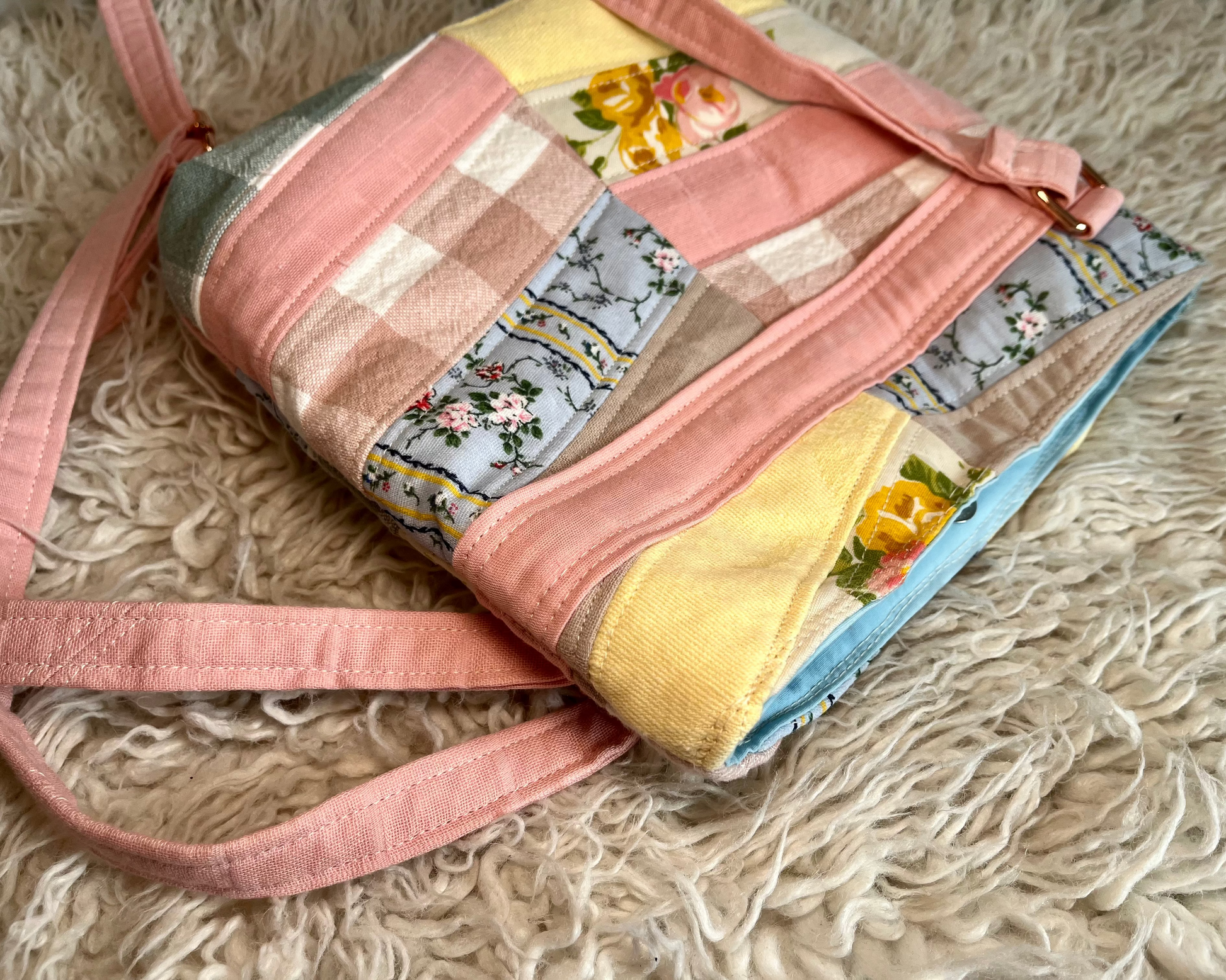 Patchwork handbag with floral and checkered patterns on a textured surface